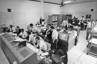 NASA engineer Jack Garman (second from left) is seen at his console in a support room for the Apollo guidance computer in Mission Control.