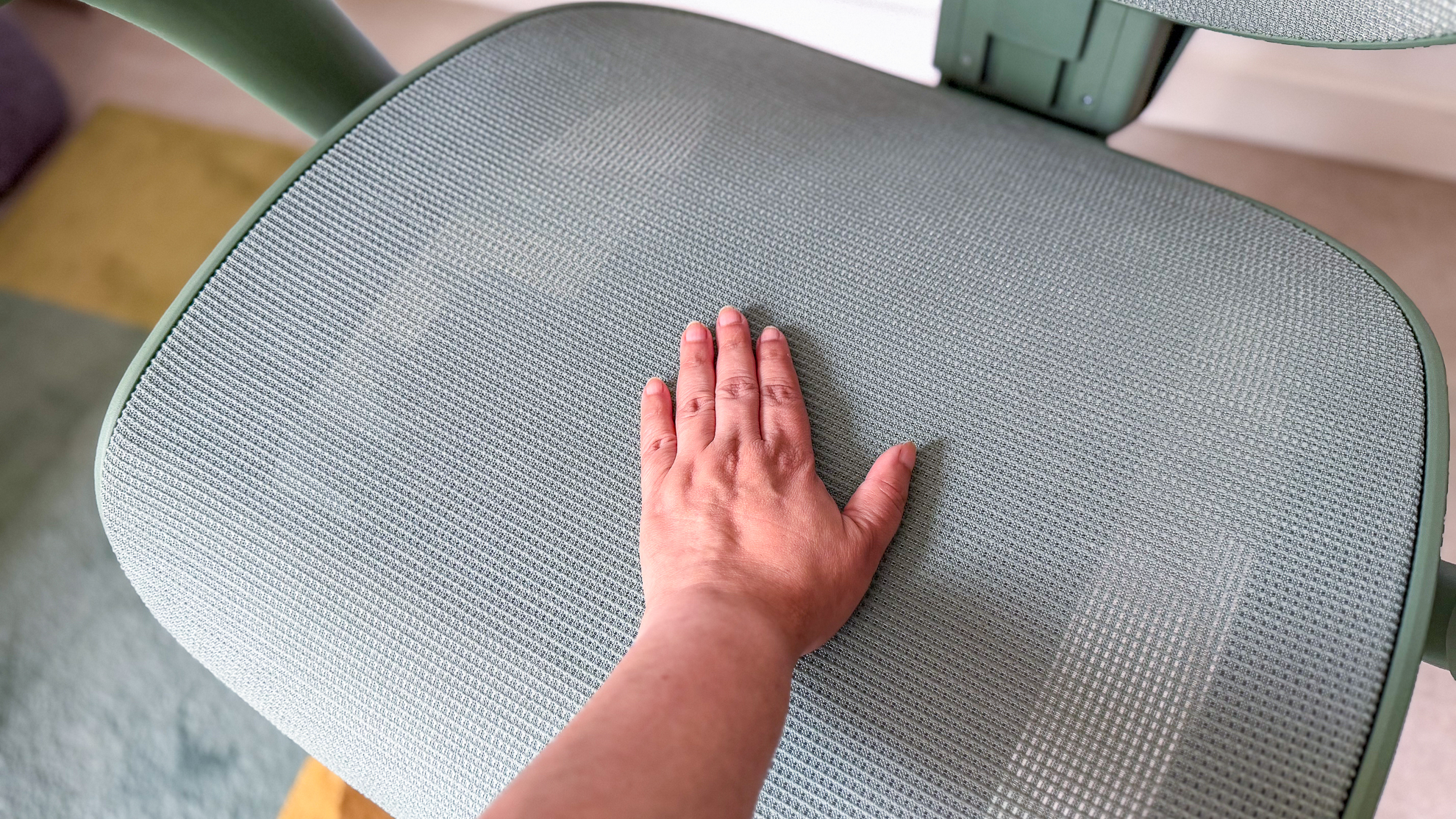 A hand on the mesh of the ErgoTune Vesby office chair seat