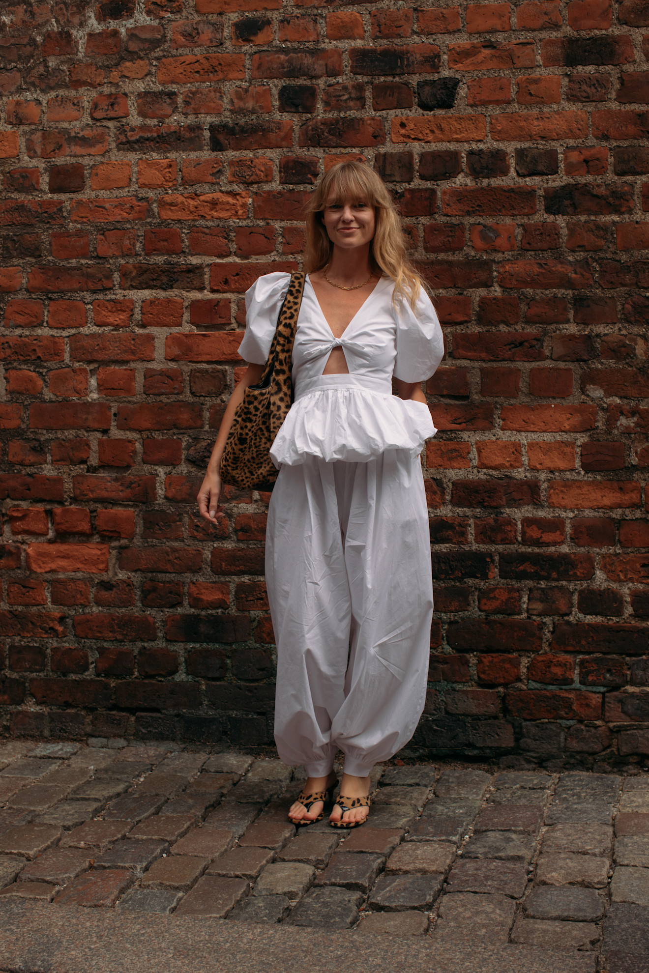woman wearing a white pair of balloon pants and a pepum top+