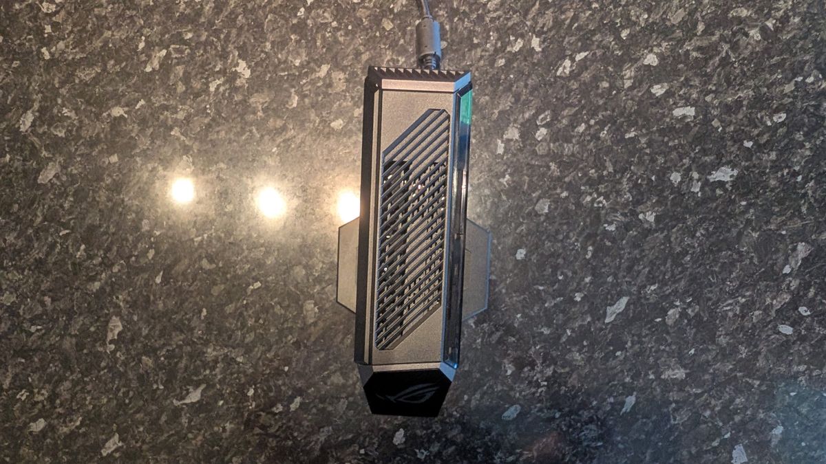 The Asus ROG NUC photographed on a dark marbled worksurface with a painted sunset in the background.