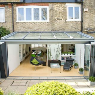 Glass lean-to extension on the back of brick property. A wall of bifold doors opens up the living space to the garden creating an inside outside space