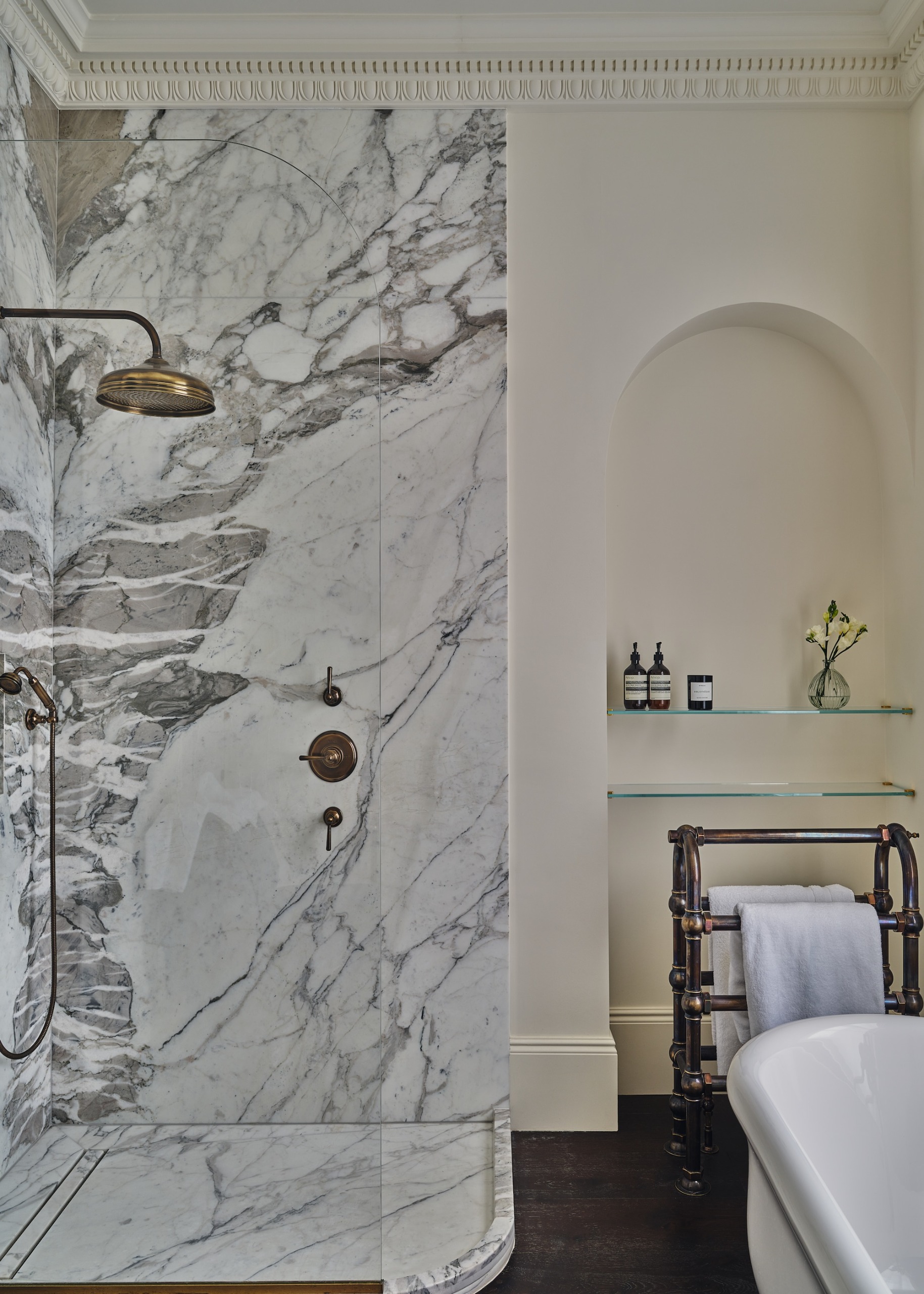 A classic bathroom shown with a marble clad shower cubicle with brass shower rose and a hand held shower