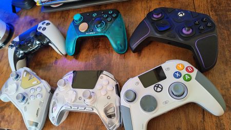 An angled photo of six pro controllers on a gaming desk
