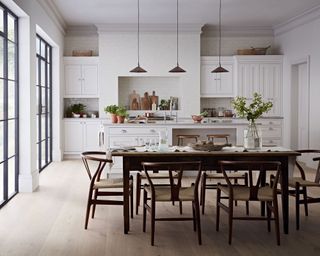 White kitchen with large dining table and steel framed windows by kitchen makers