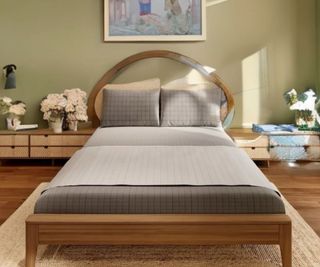 Grey grounding sheets on a bed against a light green wall.