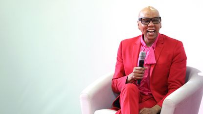 rupaul charles in a pink suit on a blue background