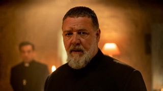 Russell Crowe in The Pope's Exorcist, he appears tense as he looks at something offscreen
