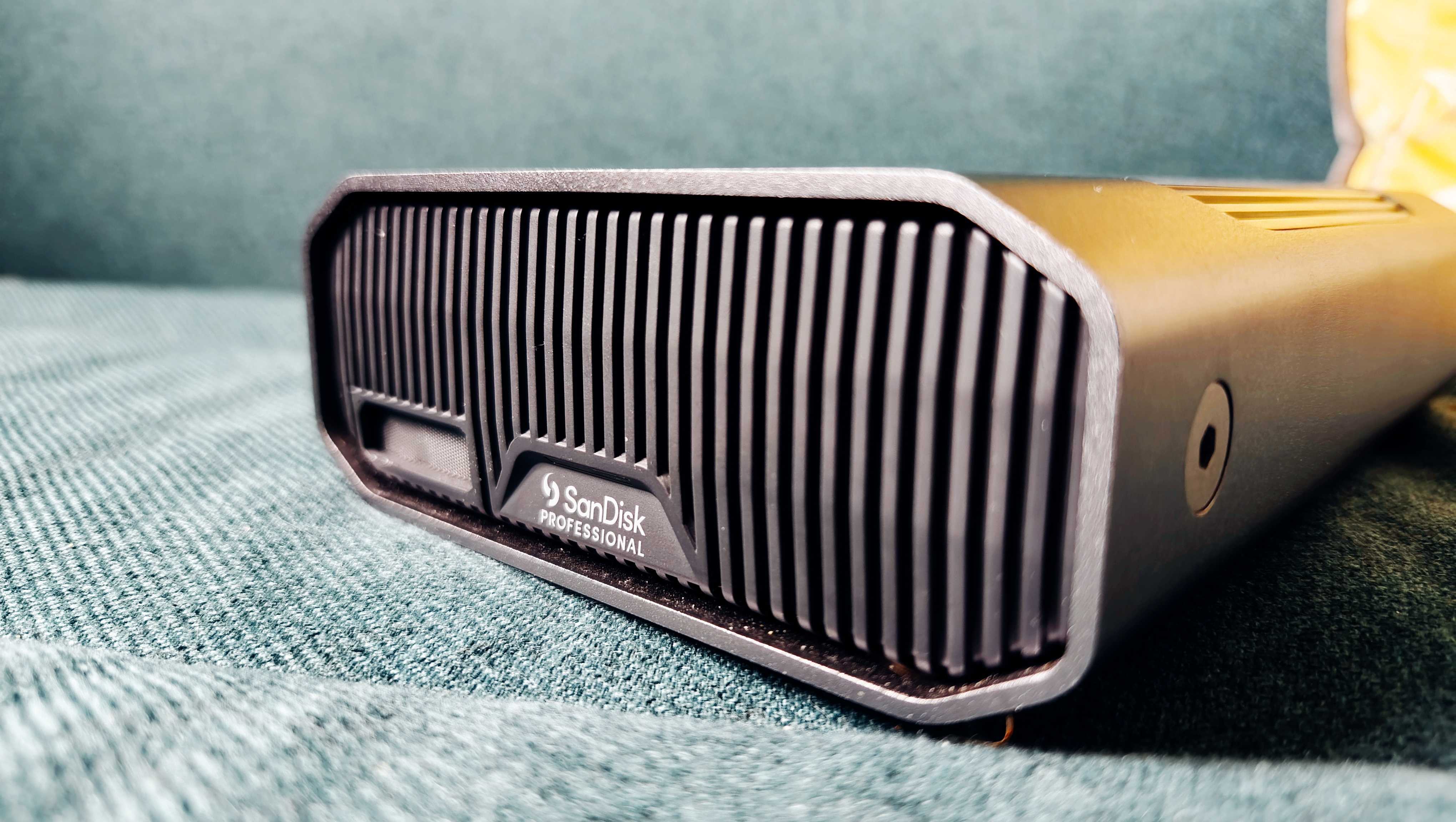 A grey and black SanDisk G-Drive sitting on a green sofa