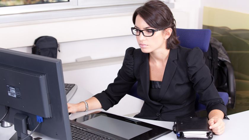 A business woman working at a desk in front of a computer.