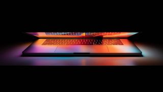 Un MacBook Pro en una habitación a oscuras con la tapa ligeramente levantada