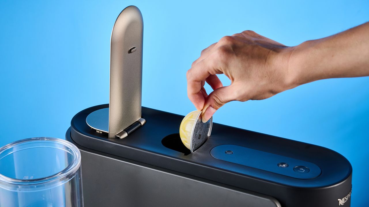 the nespresso vertuo up machine photographed against a blue background
