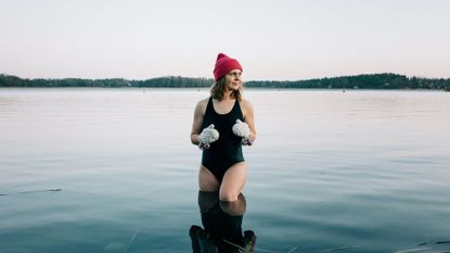 Women wears a beanie hat and swimming costume as she looks ready to swim in open water