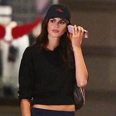 Kaia Gerber wearing a black baseball cap and sweater in NYC