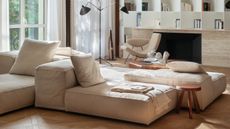 A modern living room with a beige color scheme and a set of low, modular seating in the center of the room.