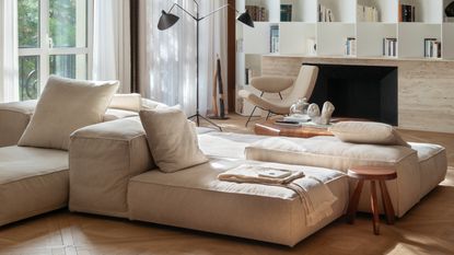 A modern living room with a beige color scheme and a set of low, modular seating in the center of the room.