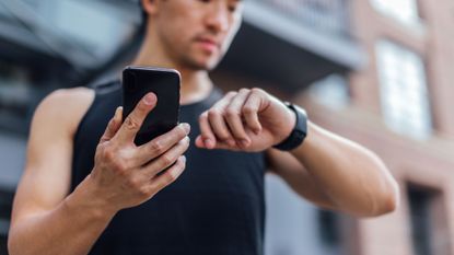 Male runner looking at watch on wrist.