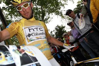 With minutes to spare before start, Mark Cavendish appears from the team bus and is instantly swamped by fans and autograph requests.