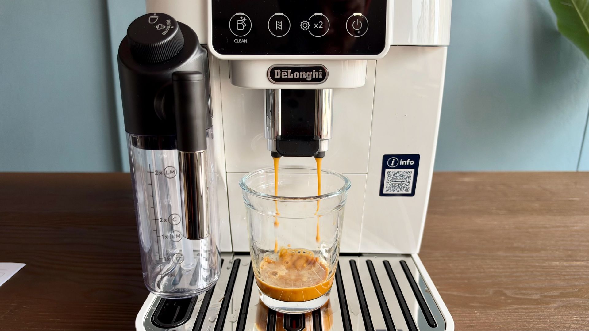 De'Longhi Magnifica Start with a coffee pouring into a glass cup