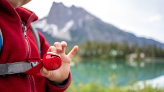 A hiker holding a bear bell with mountains in the background