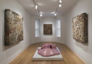 Three artworks consisting of fabric pieces compressed into squares, and a fourth artwork on a white plinth on the floor