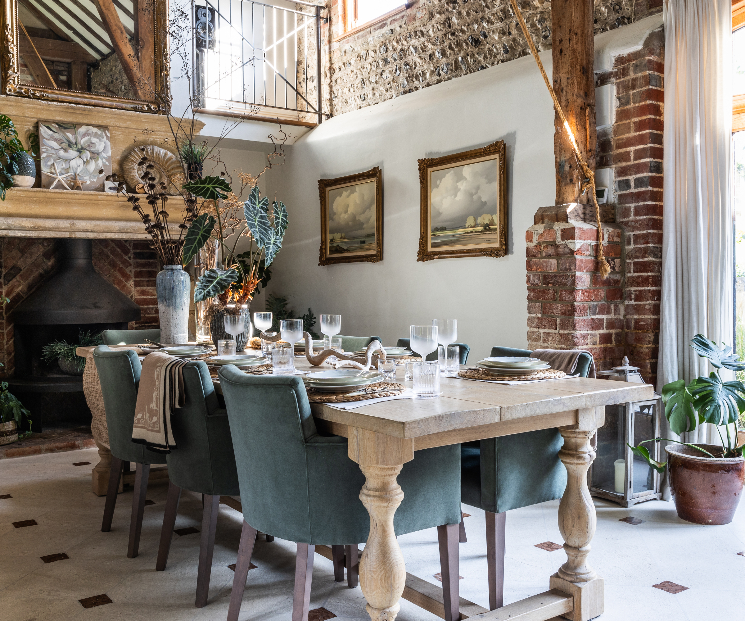 dining room with with exposed brick walls, large fireplace, wooden beams and wooden table with blue upholstered chairs