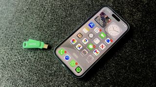iPhone 15 Pro on a fabric surface with USB-C flash drive