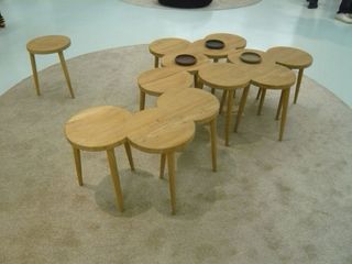 Twelve three-legged stools merged together to form an abstract table