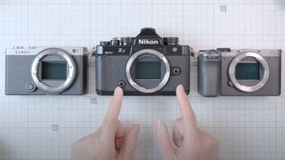 Hands pointing to the Nikon Zf, next to the Lumix S9 and Sony A7C II