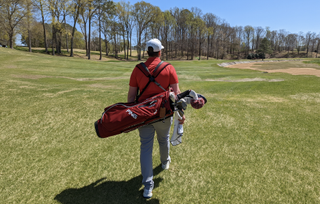 Golfer pictured from behind carrying a golf bag
