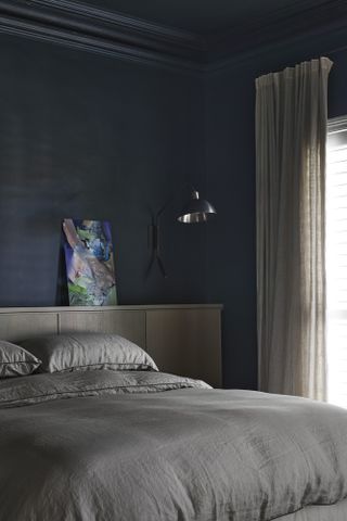 A bedroom with a dark gray-green wall color