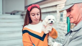 Woman signing for package while holding her dog