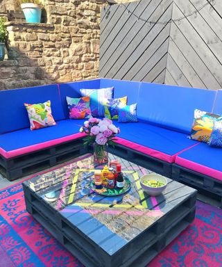 An outdoor living area with black pallet coffee table with glass top