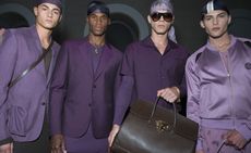 Four male models wearing clothing by Versace in shades of purple.