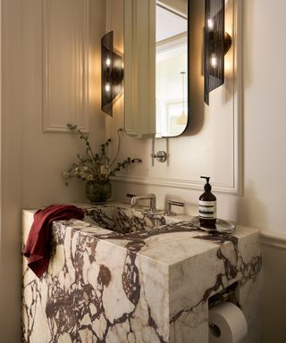 white small bathroom with paneling, marble basin, modern mirror and wall lights