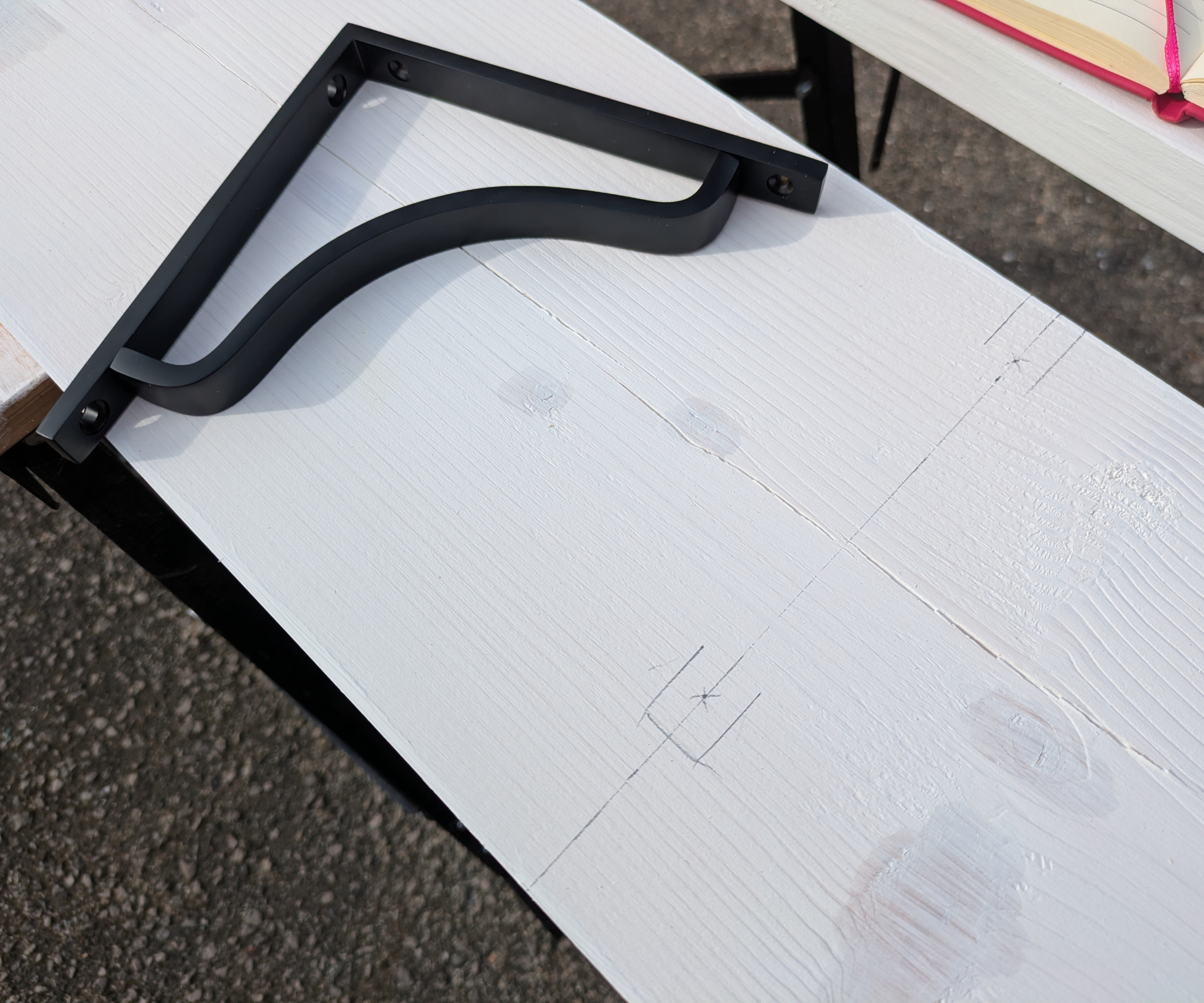A bracket resting on a shelf which has been marked up in pencil ready for drilling