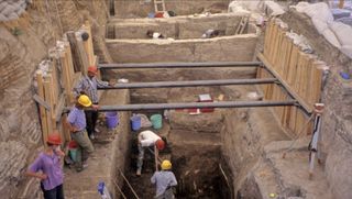 A group of people excavating a house from light-colored stone