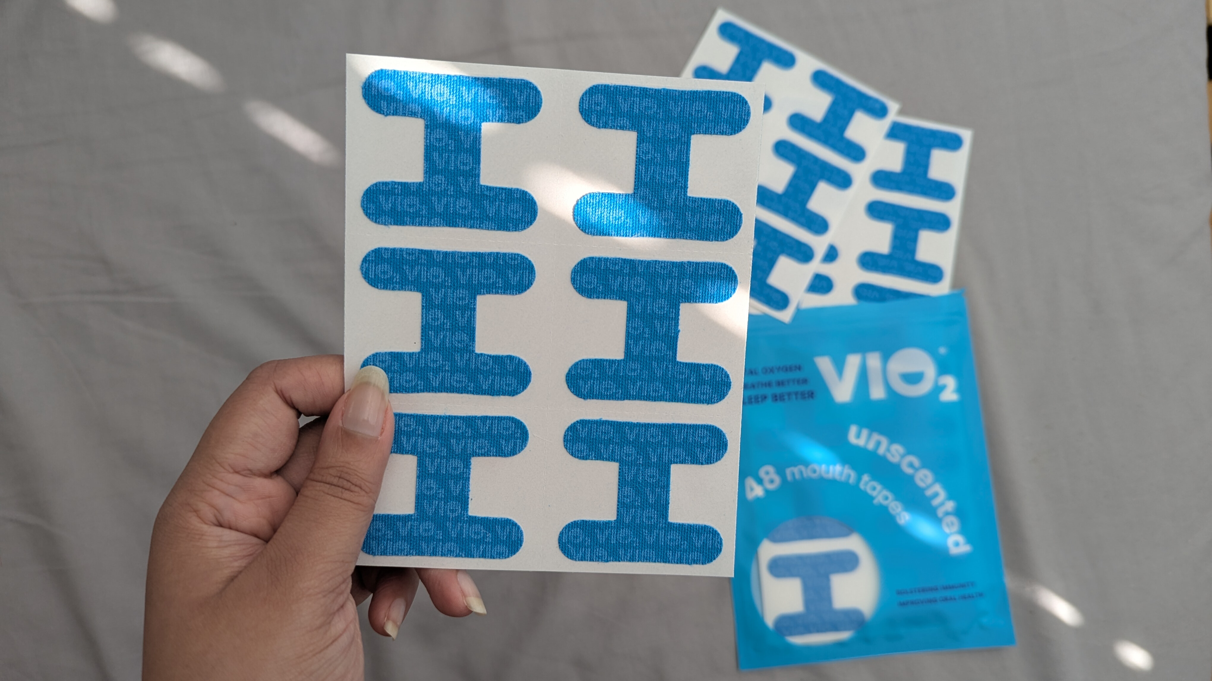 Hand holding a strip blue I shaped mouth tapes