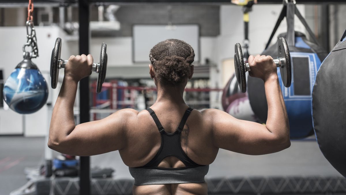 Muscular bodybuilder male athlete demonstrates her body in the gym