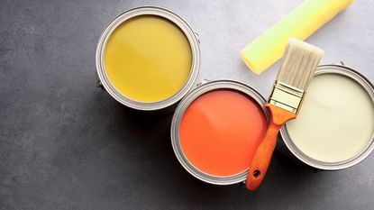 Paint tins with a brush laid on top