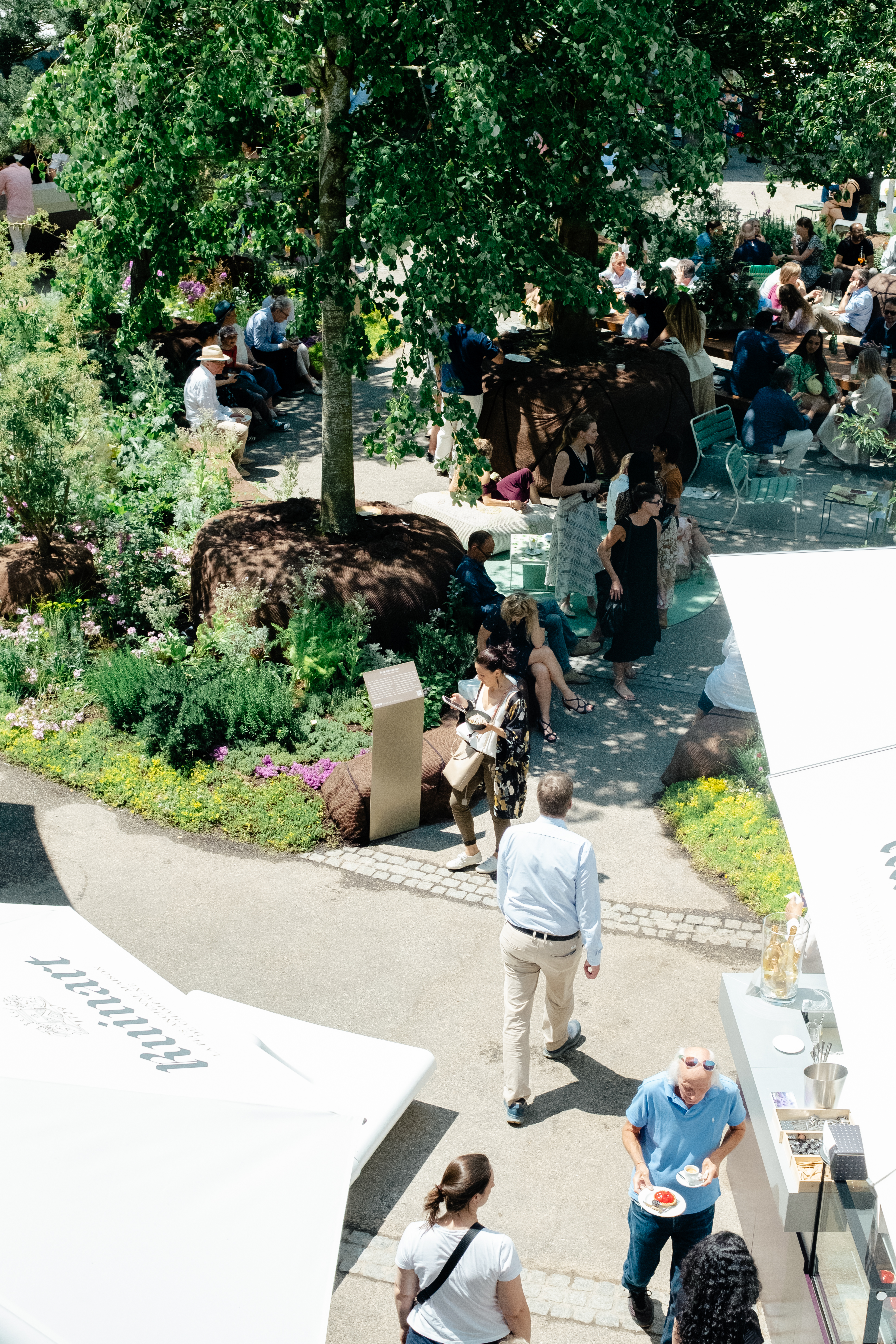 A series of lifestyle images depict people at leisure and play in a Swiss town bathing in sunshine, whether enjoying the weather near the river bank or abstract painting murals at an art fair.