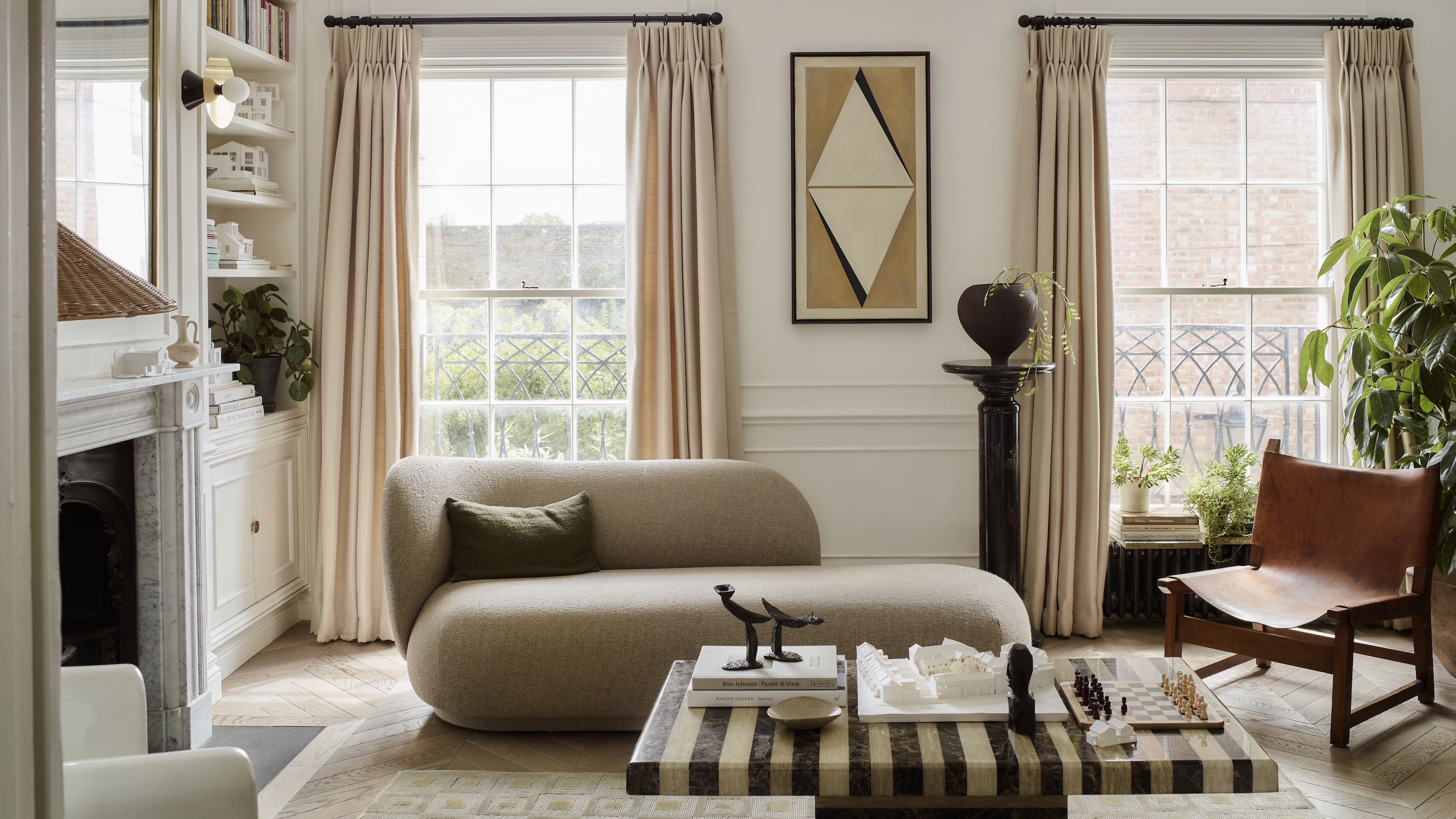 neutral living room with curved sofa, striped marble coffee table and cream curtains