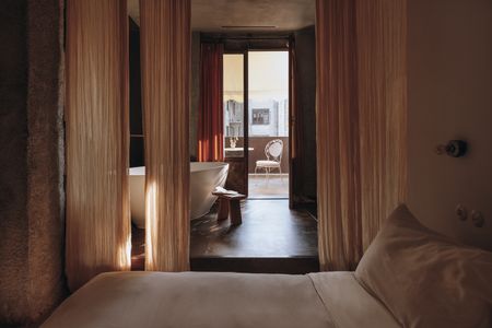 A bedroom with curtains separating the sleeping space from the bathtub