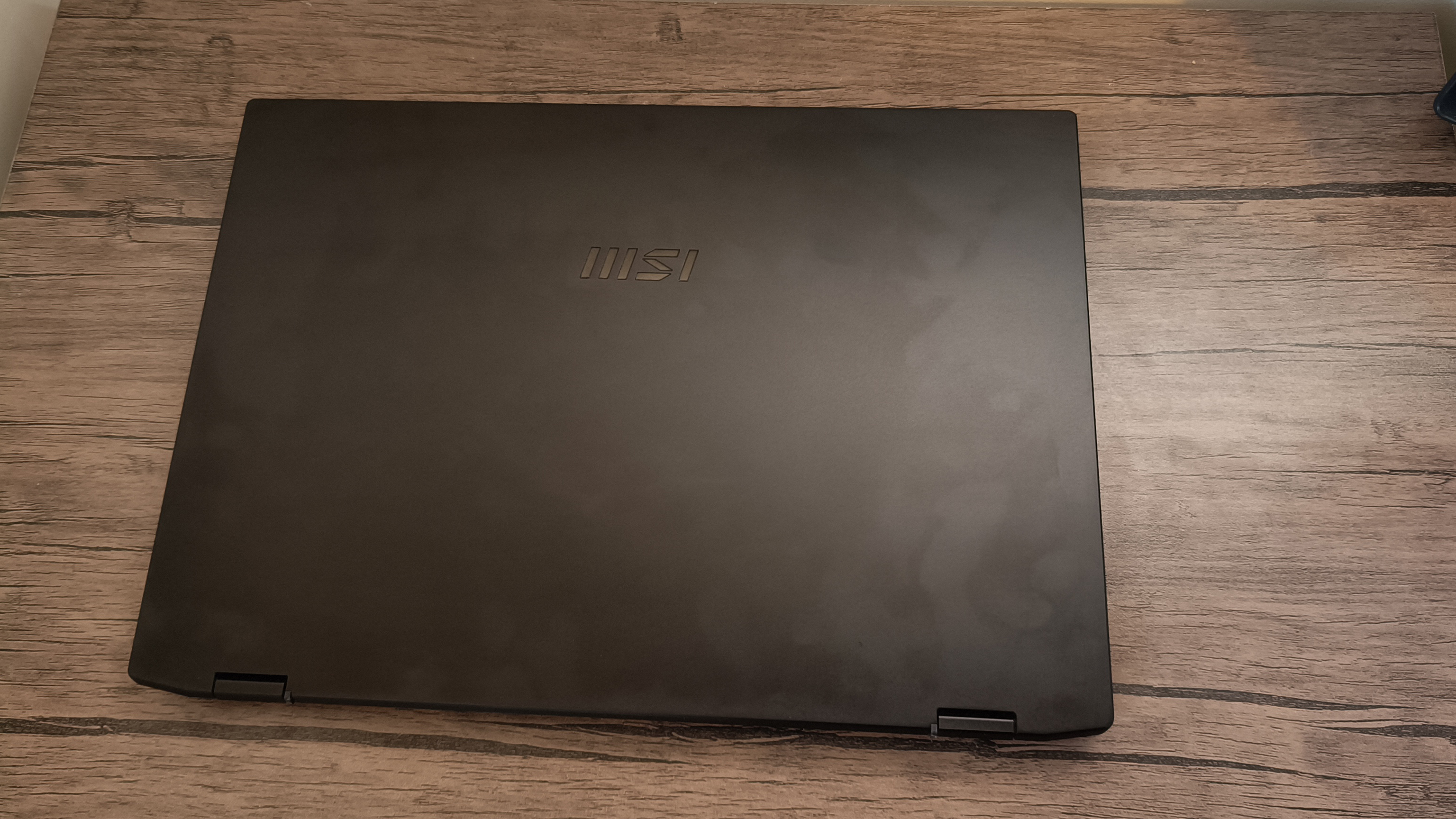 A black MSI Summit E16 Flip Evo laptop on a brown wooden table