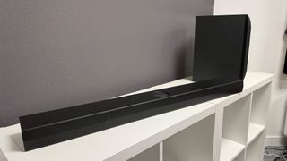 LG S70TY soundbar package on white shelving unit in front of grey wall