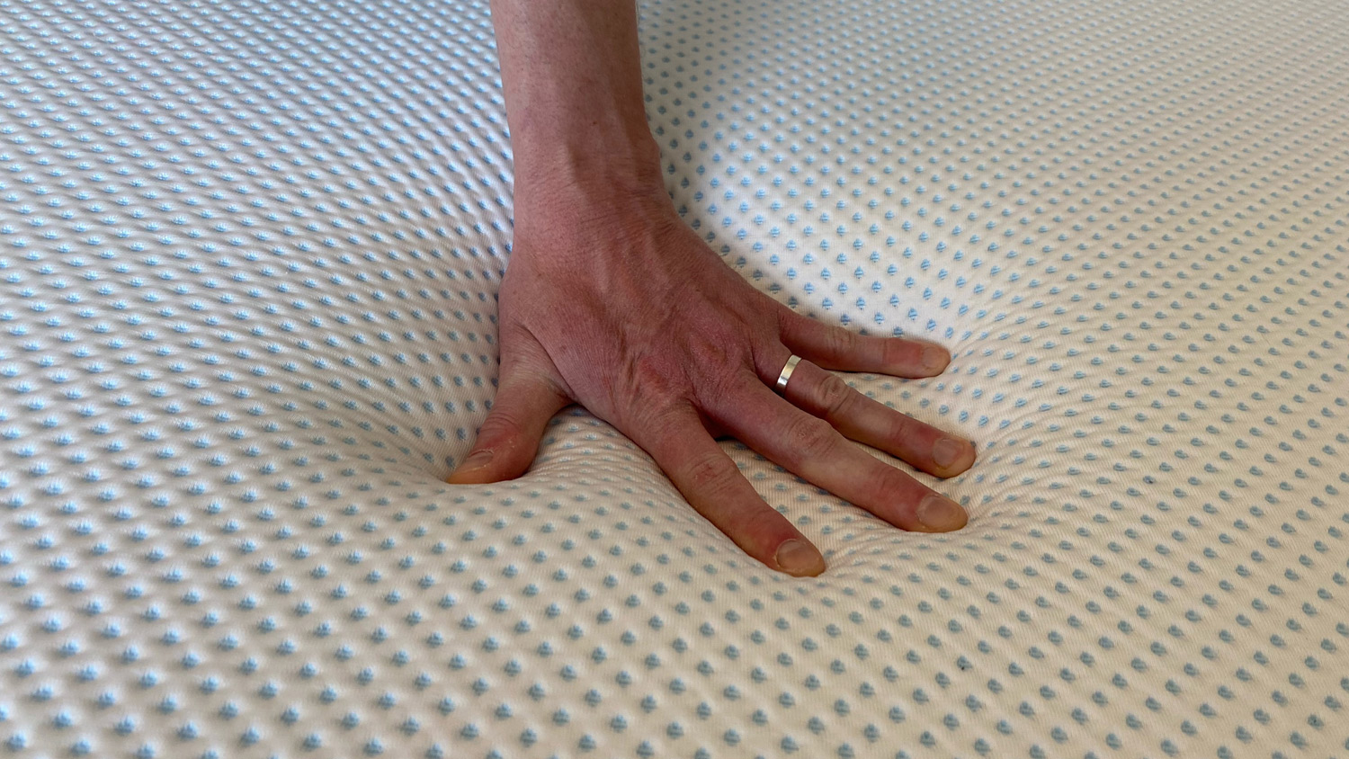 A hand pressing down on the Amerisleep AS3 Hybrid mattress