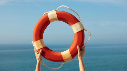 A life preserver is held up against the ocean horizon.