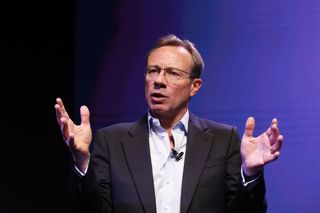 BT CEO Philip Jansen gestures with his hands raised while speaking during a news conference against a black to purple gradient background