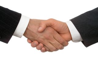A closeup of two people wearing suits shaking hands