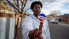 Young man holding up an "I Voted" sticker