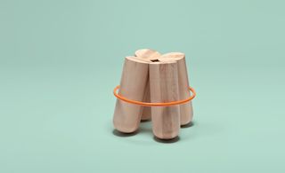 Stool with 4 solid log legs held together by a contrasting metal ring.